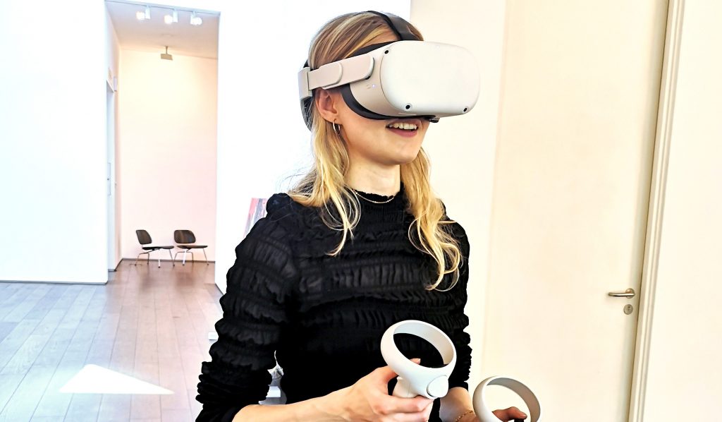 Photo shows a woman viewing an art exhibition on Vortic in a Meta Quest headsset
